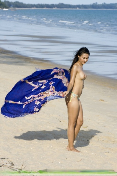 Asian amateur wanders along a beach in just her bikini bottoms