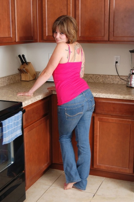 A plump girl removes her jeans on her way to posing nude on the kitchen floor during the hour.