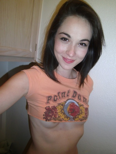 Emily Grey, a brunette, rubs her shaved vagina and takes a selfie.