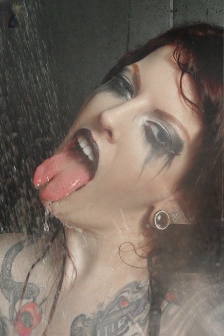 Redhead with tattooed tattooed legs and arms, Penny Poison takes great poses in the shower.