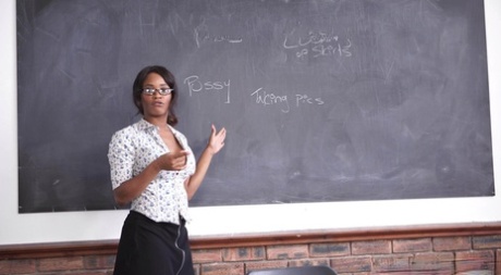 Чернокожая школьная учительница Кики Минаж позирует под юбкой без трусиков на своем столе