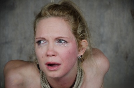 During her bondage, Rain Degrey, a blonde woman in bondage, tears from the pain caused by breast torture.