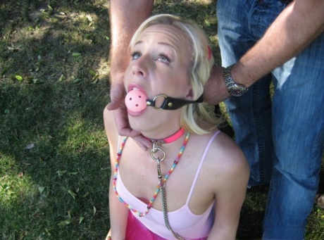 An outdoor encounter involves young blonde Eden Adams being held back and given a hard kiss before being collared and ball gagged.