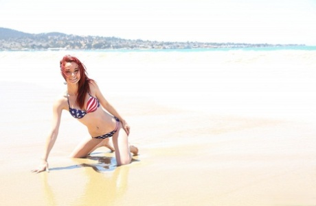 On a beach day, Kylie Cole models a USA-themed bikini while exchanging cutoffs with her pale red hair.