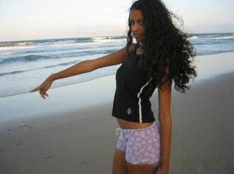 Polliana, a Brazilian girl, is seen wearing a barefooted top and lifting it up while lounging on the beach.