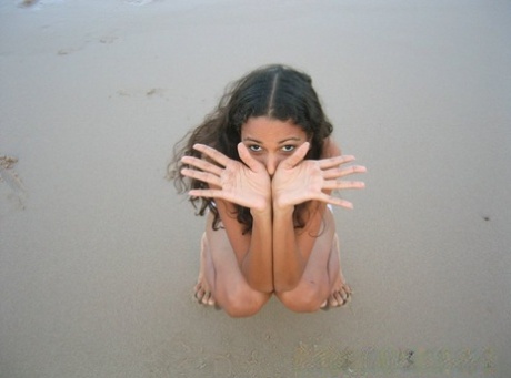 Polliana, who is a Brazilian girl, stands barefoot and pulls up her swimsuit at the beach.