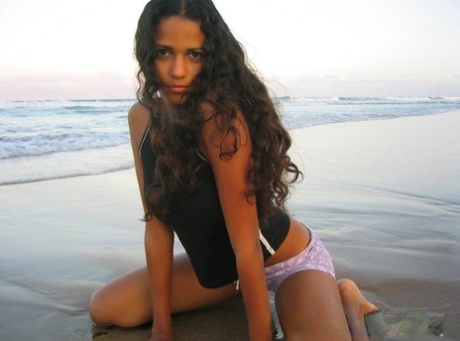 On a beach in Brazil, Polliana stands tall in her tank top while walking naked.