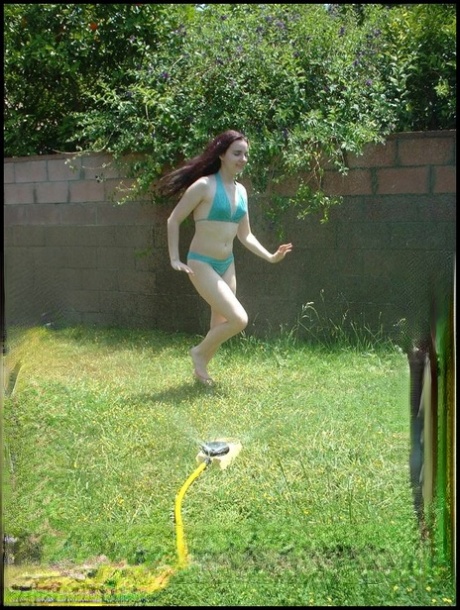 Pale-haired squirt Amber Lily shows off her buttocks while using a garden hose to wean herself.