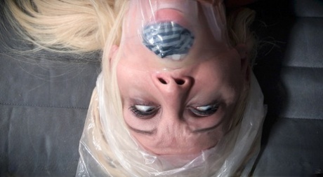 In a storage room, the peculiar blonde Kenzie Taylor is tied up and gagged.