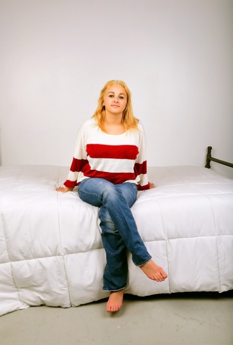 With her large breasts and buttocks, Aria Skye, a chubby blonde, sprawls on top of her bed.