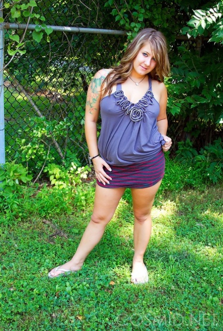 Plump amateur removes cotton underwear against a chain link fence