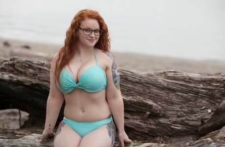 Kaycee Barnes, a beautiful plump redhead with seductive appeal, is seen in public without glasses while standing naked.