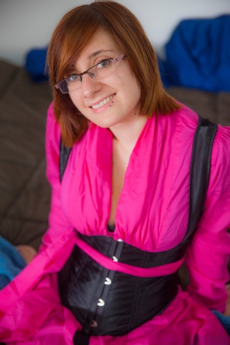 Chelsea Bell, who is wearing glasses, disrobes to display her large tits and bald muffs.