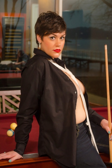 A pool table is where Annalise, a thick and thin woman with short hair, exposes her large breasts and buttocks.