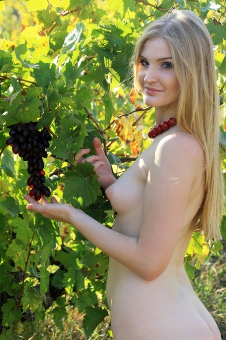 The blonde model Tinaa performs impressive nude poses while picking grapes from the garden.