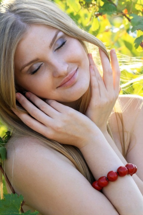 The blonde model Tinaa performs impressive nude poses while picking grapes from the garden.