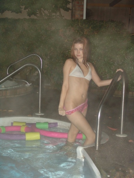 In a pool at night, Korina Bliss, a red-haired lad, removes her bikini braces.