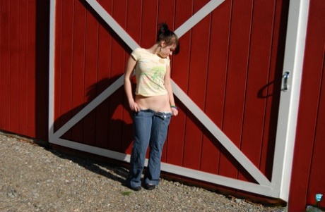 Молодая любительница Эмили Лав стягивает джинсы перед раздвижной дверью сарая