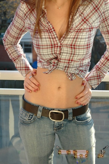 A non-nude image of a redheaded country girl is depicted, dressed in a tied up shirt and jeans.