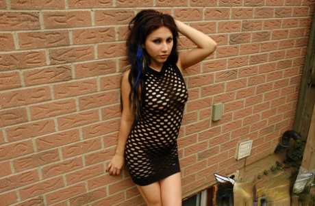 Petite teen with a wild look to her removes mesh dress to pose naked outdoors