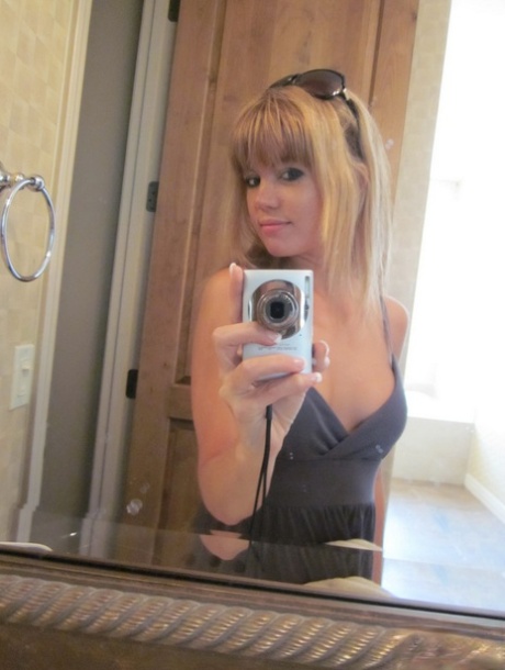 At a restroom, the cute young girl named Diddylicious takes selfies while wearing a topless vest.