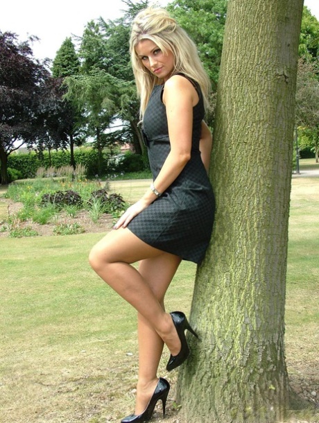 Hot blonde in a black gown and low-heeled stilettos, showing off her broad legs.