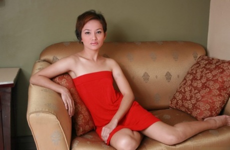 A young Asian girl with short hair removes her red dress for her nude debut.