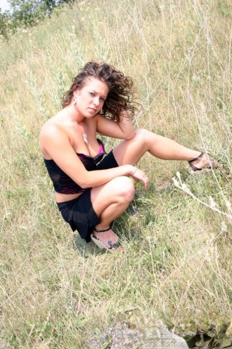 Teen amateur shows some cleavage during a SFW shoot out in a field