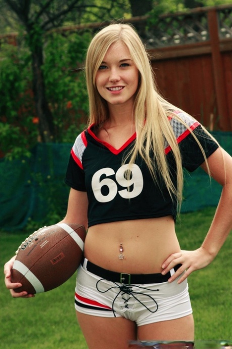 Jewel, who is beautiful blonde, poses nude while holding a football.