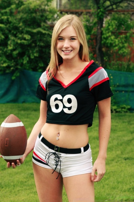 Wearing her beautiful blonde hair, Jewel poses nude while holding a football.