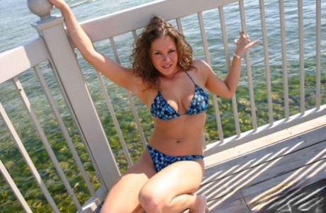 Teen amateur models in a bikini on a balcony overlooking a body of water