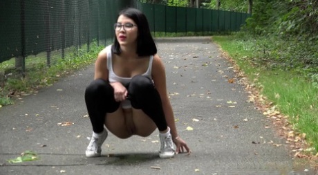 Glasses wearing chick pulls down her legging for a quick piss on on paved lot