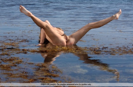 Blonde girl, Rubie is naked and playing in the water with her sexy bare feet.
