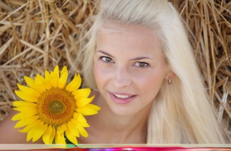 The attractive blonde Vika D displays her baldness on a round bale.