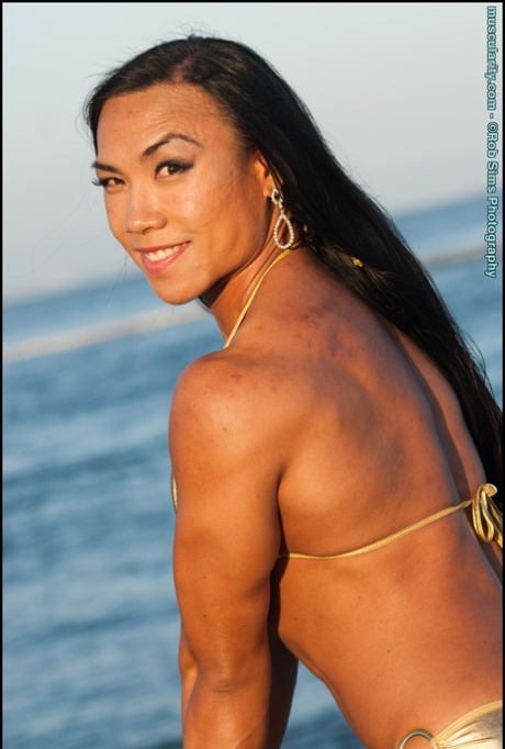 Asian Bodybuilder Tram Nguyen Flexes On A Beach In A Gold Bikini