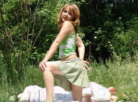 A beautiful young girl named Liza displaying her firm, round chestets on a grass-covered blanket.