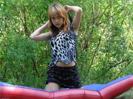 Teen first timer Liza strips naked on an air mattress surrounded by trees