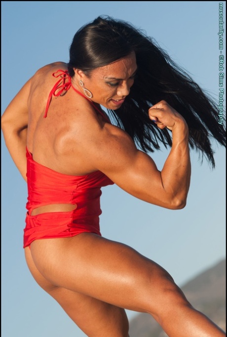 On a beach, Tram Nguyen, an Asian bodybuilder, displays her muscle power while wearing swimsuits.