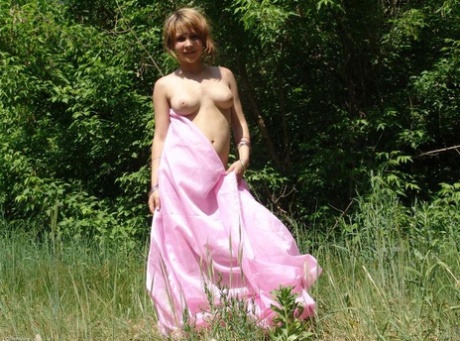 In front of a tree line in a field, Liza, an 18-year-old first timer, goes naked.