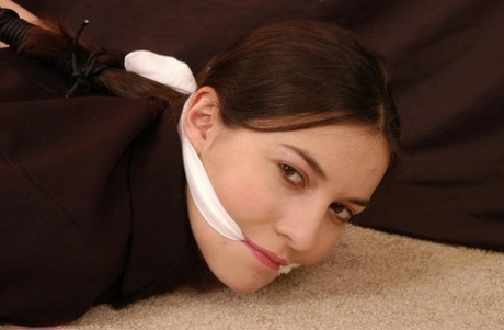 Brunette teen is hogtied in her clothing while sporting a cleave gag