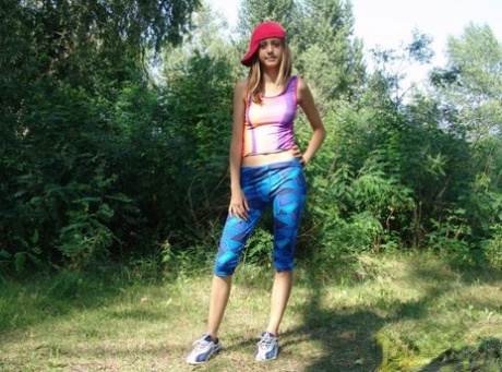 Blonde teen goes to lift up her tank top with her ball cap on sideways