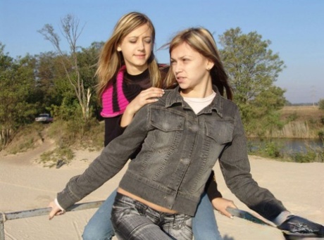 At the beach, young girls dressed in denim jeans and jackets hold hands without clothing.