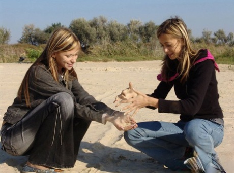 In the middle of the beach, young girls in denim jeans and jackets hold hands while wearing their clothes off.