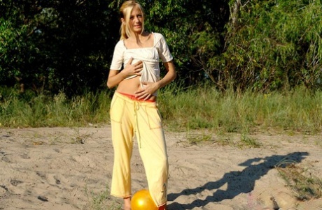 Young blonde reveals her firm boobs as she disrobes outdoors
