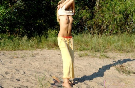 While disrobing herself outside, the young blonde exposes her firm chest area.