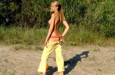 Exhibiting her firm breasts, a young blonde exposes herself outside in the dressing room.