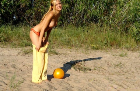 Young blonde reveals her firm boobs as she disrobes outdoors