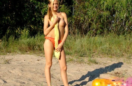 The blonde girl exposes her firm breasts as she goes for a walk in the open air.