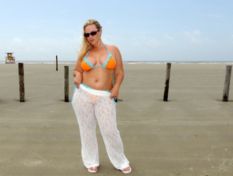 Dee Siren, an amateur BBW, frees large figures from a bikini on the beach.