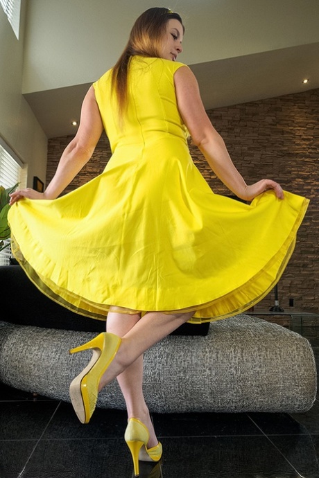 A naturally reddened individual climbs up onto her yellow dress, grabbing hold of it and snatching it.